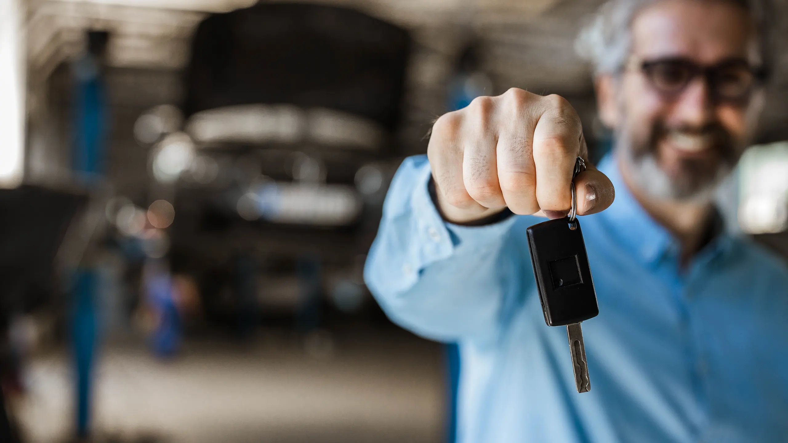 Autech Wesel – Ihre Auto-Spezialisten in Wesel – Leistungen – Mann hält Schlüssel, unscharfer Hintergrund